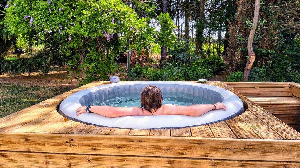 a woman is laying in a hot tub at Gîte de la Verdière Spa Pool Valley in Le Sourn
