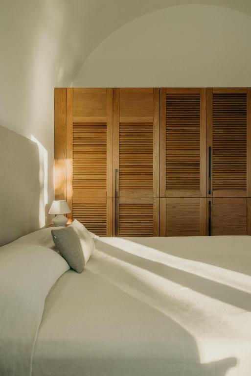 a bedroom with a large white bed with wooden cabinets at Damma Villa in Kamari