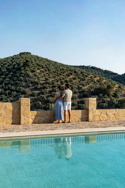 two people standing next to a swimming pool at Cortijo La Presa in Priego de Córdoba
