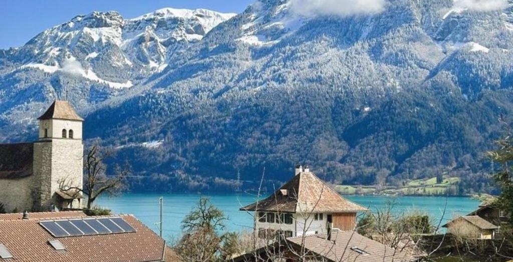 a church and a lake with mountains in the background at Sam's Lakeview apartment in Ringgenberg