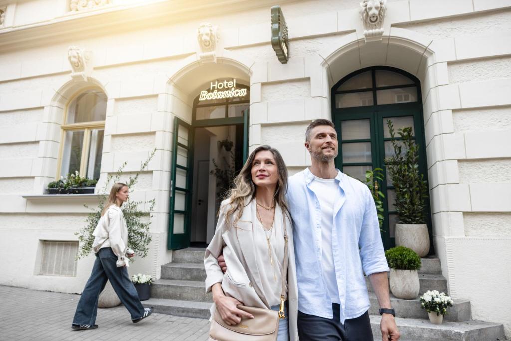 a man and woman walking in front of a building at Hotel Botanica by goodnite cz in Brno