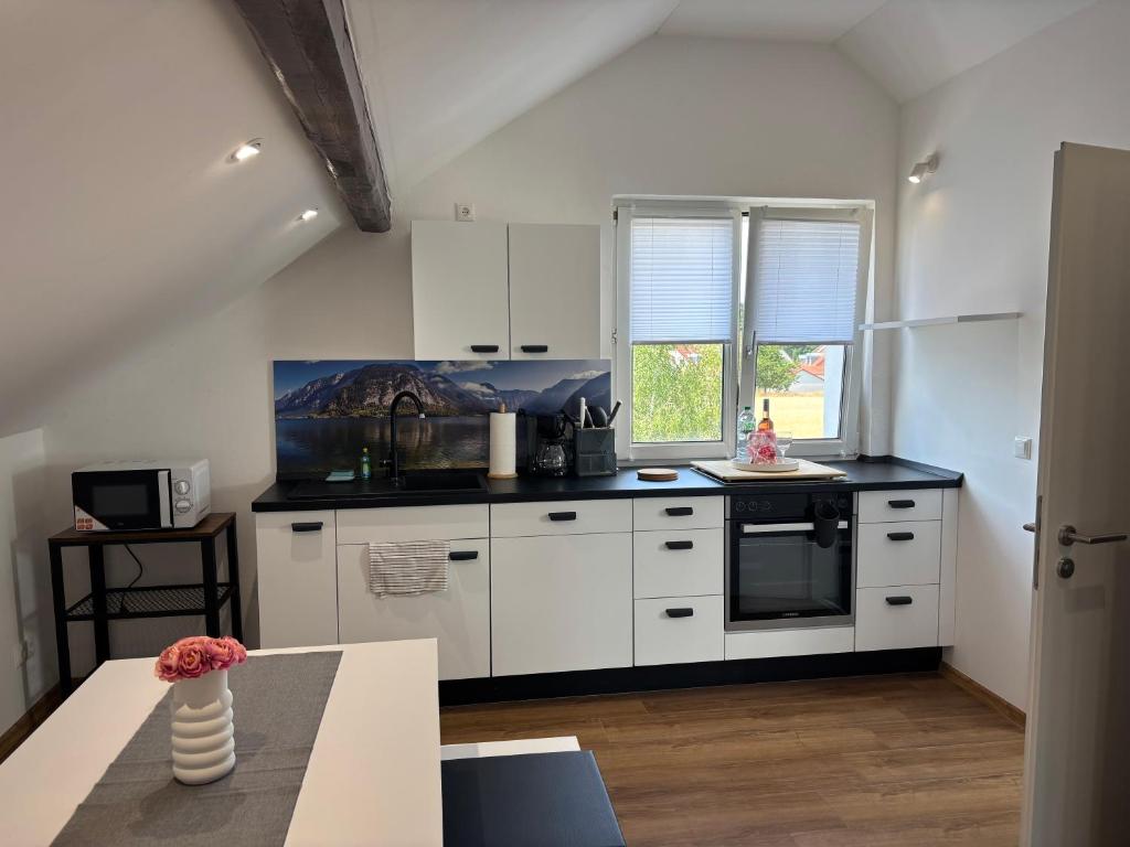 a kitchen with white cabinets and a black counter top at Vilseck Stay - Studio Suite in Vilseck