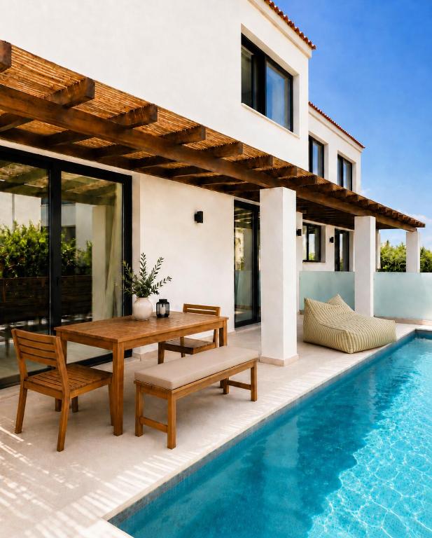 a villa with a pool and a wooden table and benches at athanasian side sea view home in Polychrono