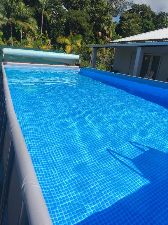 a swimming pool with blue tiles on the side of a house at Gite, Route Des Laves in Saint-Philippe