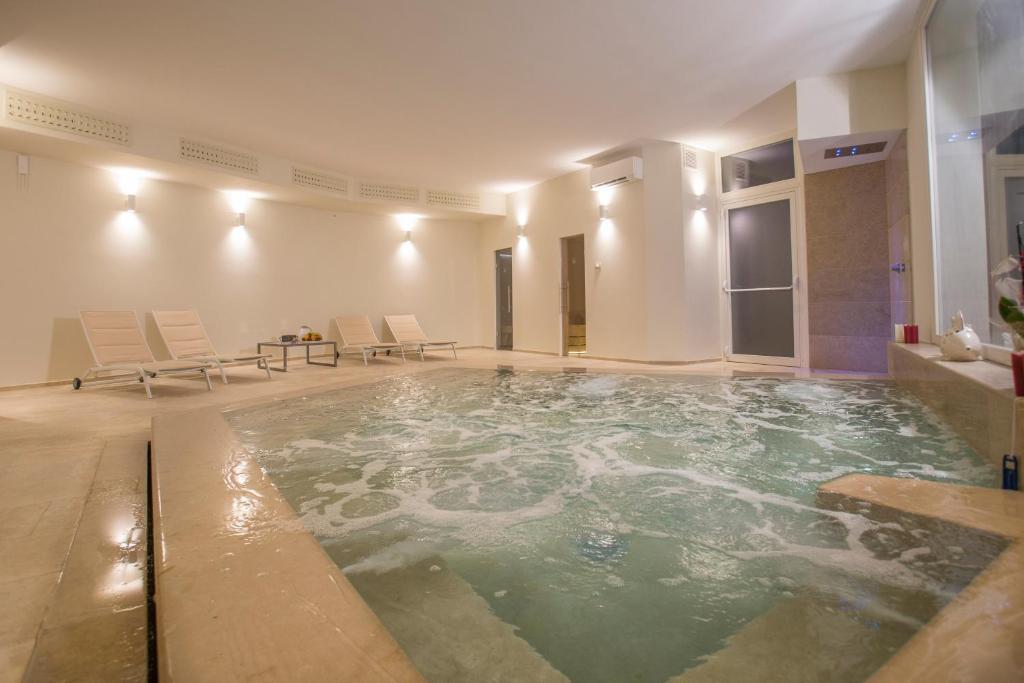 a swimming pool in a room with chairs and a table at Masseria Mongiò dell'Elefante in Otranto