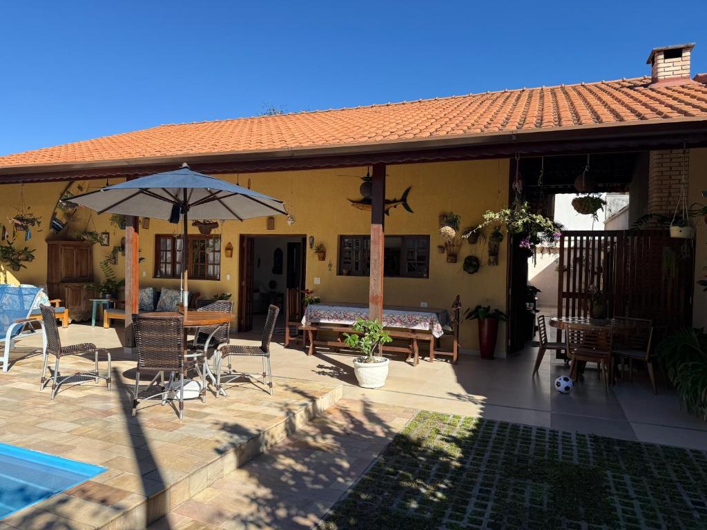 a house with a patio with chairs and an umbrella at casa 300 mts da praia in Juquei