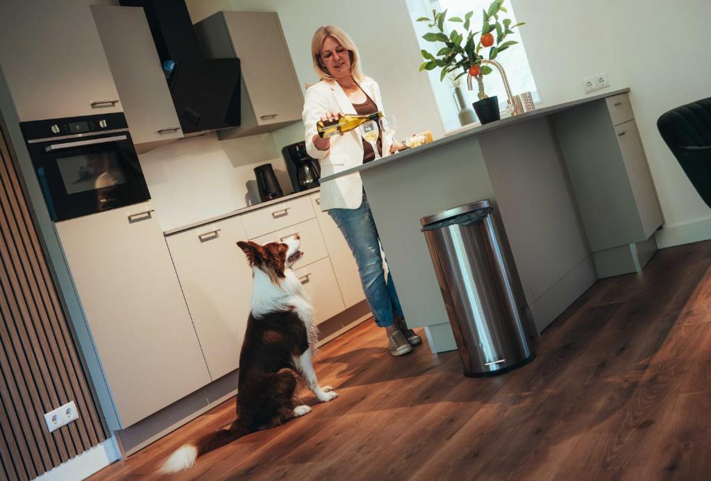 a woman standing in a kitchen next to a cat at Natuurhuisje 'n Snuffelstee in Markelo