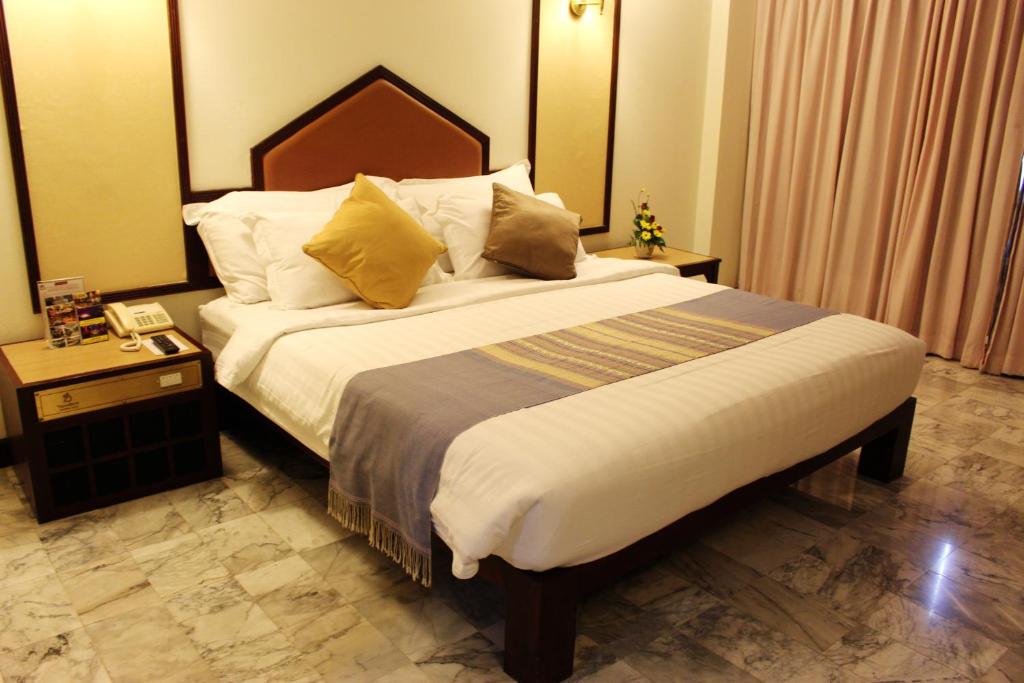 a bedroom with a large bed with a wooden headboard at Seeharaj Hotel in Uttaradit