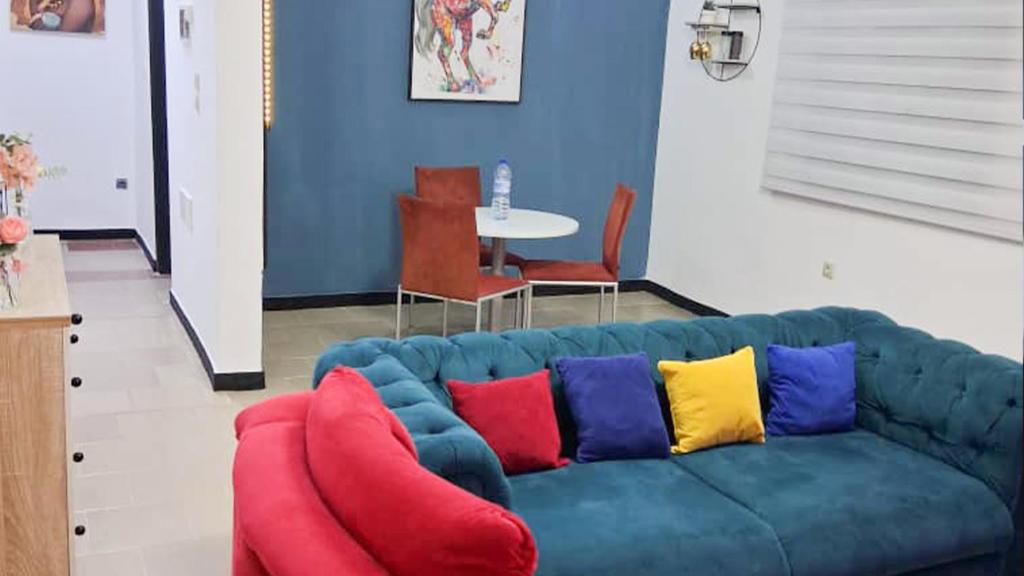 a blue couch with colorful pillows in a living room at Cotonou AMAZONE GUEST in Cotonou