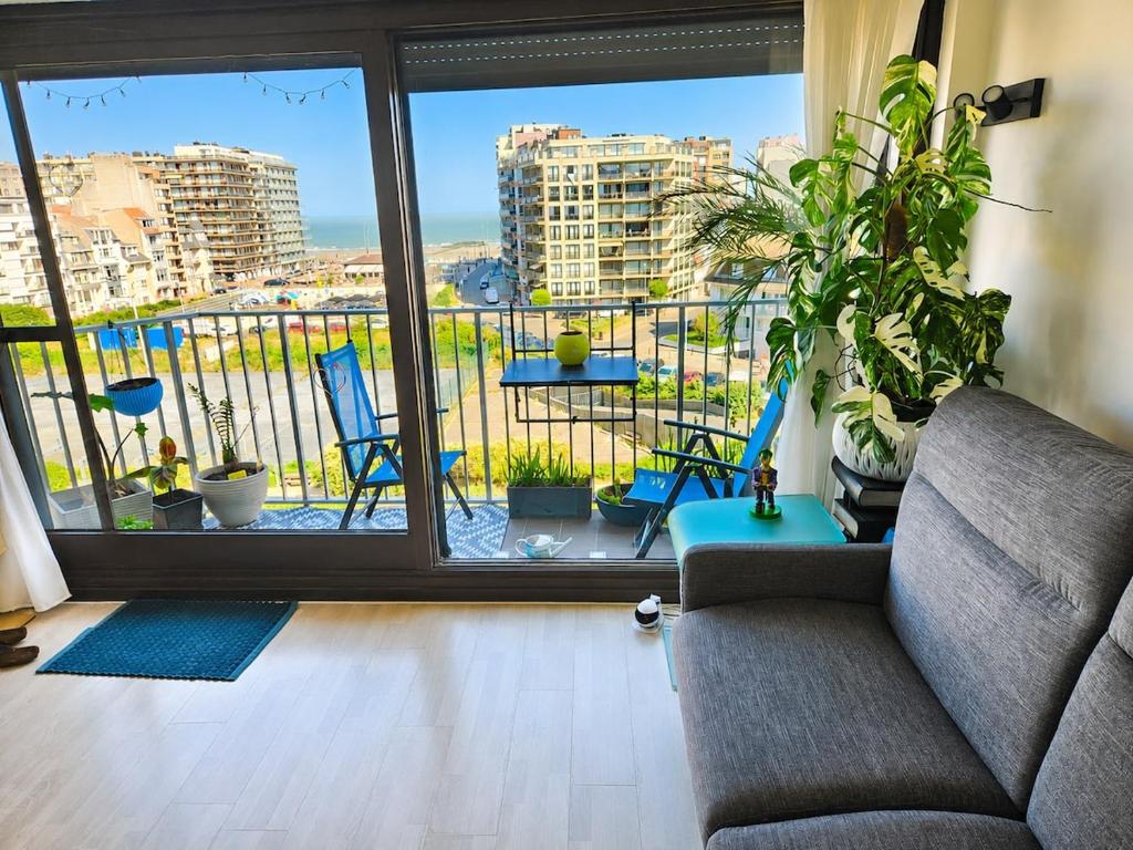 a living room with a couch and a large window at Modern Studio with Sea View and Balcony in Middelkerke