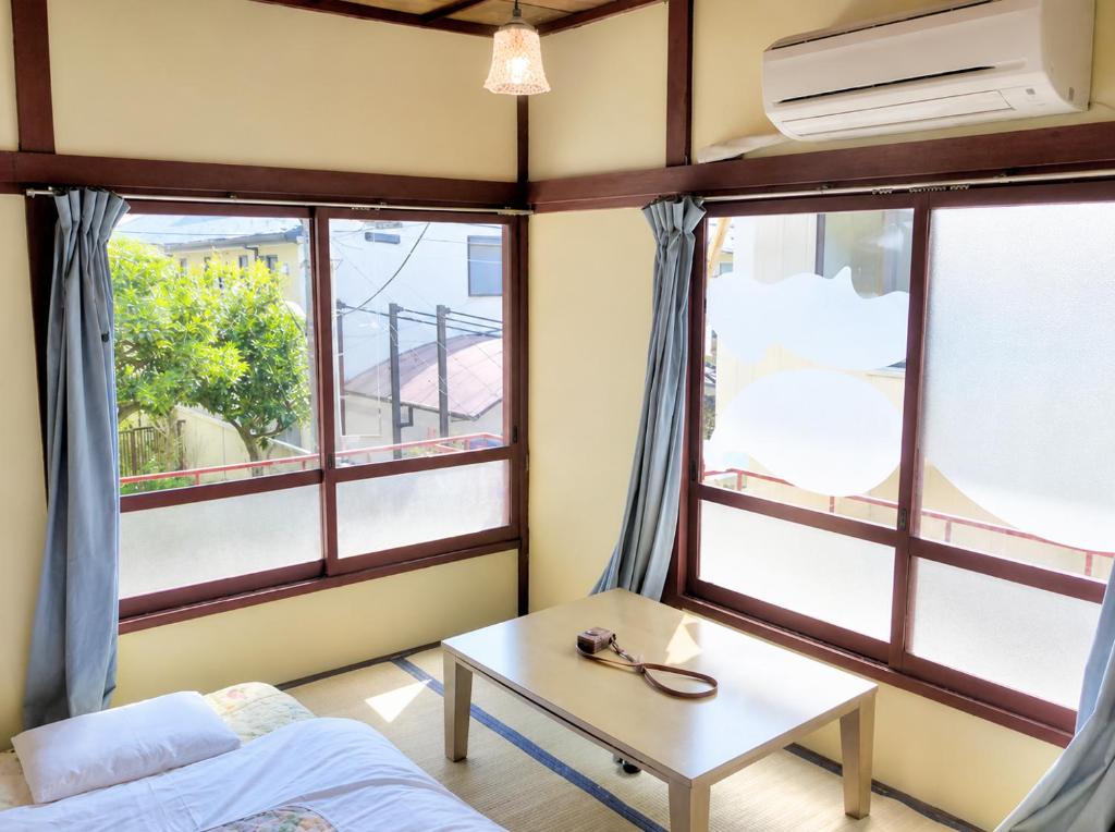 a room with windows and a bed and a table at Artist's Studio in Mitaka