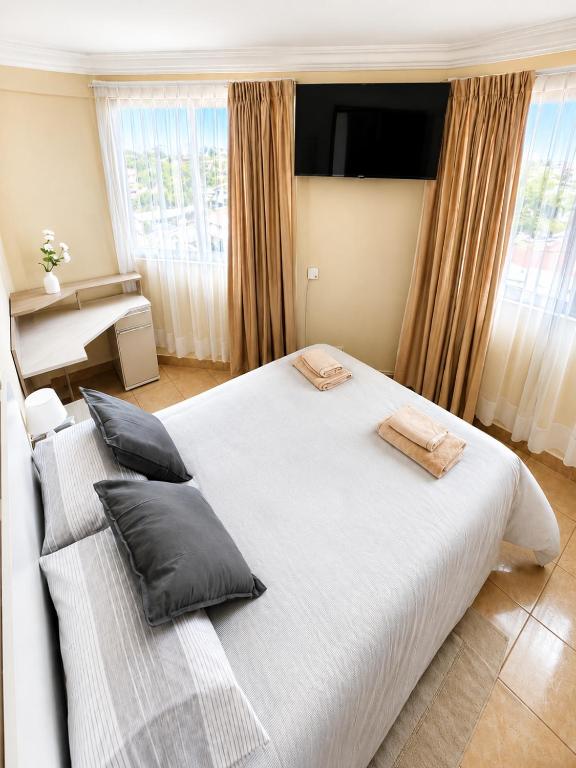 a bedroom with a large white bed with pillows at Hipódromo Sky Penthouse in Cochabamba