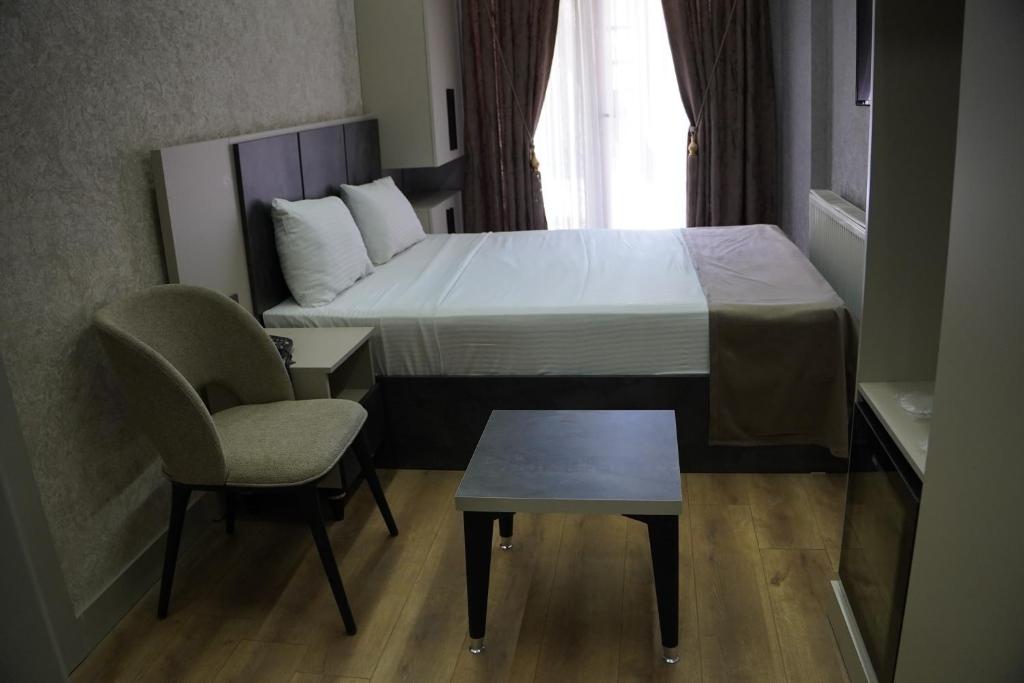 a bedroom with a bed and a chair and a table at Real Hotel Van in Ipekyolu