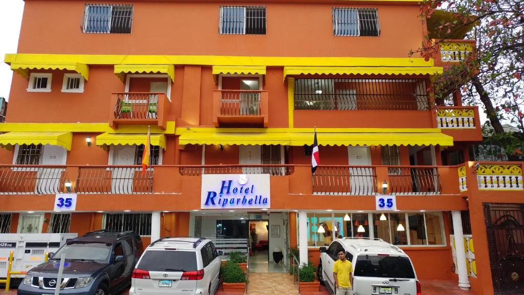 een groot oranje gebouw met auto's ervoor geparkeerd bij Hotel Riparbella in Santo Domingo