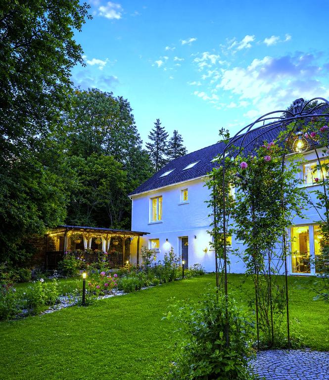 a white house with a garden in front of it at Ferienhaus Rosengarten Mürlenbach in Mürlenbach