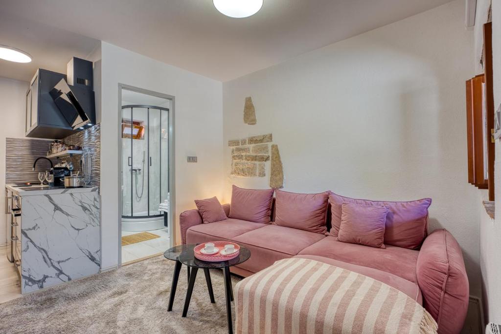 a living room with a pink couch and a table at Holiday House Ante in Žminj