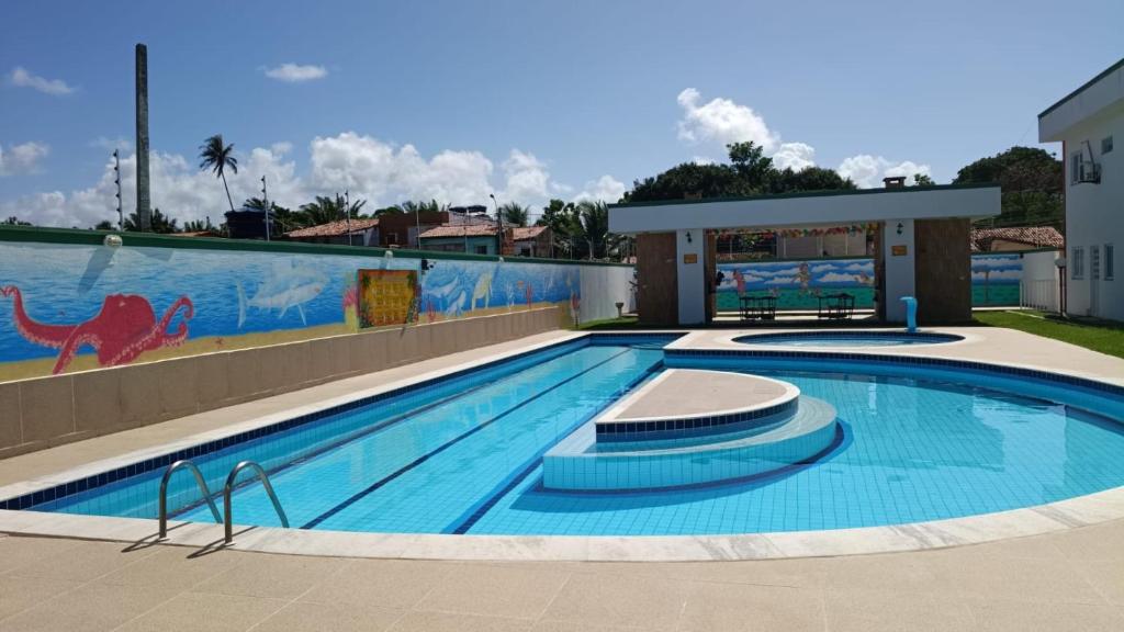 a large swimming pool with a mural on the side of a building at Praia do Frances-Riviera do Frances casa 37 in Marechal Deodoro