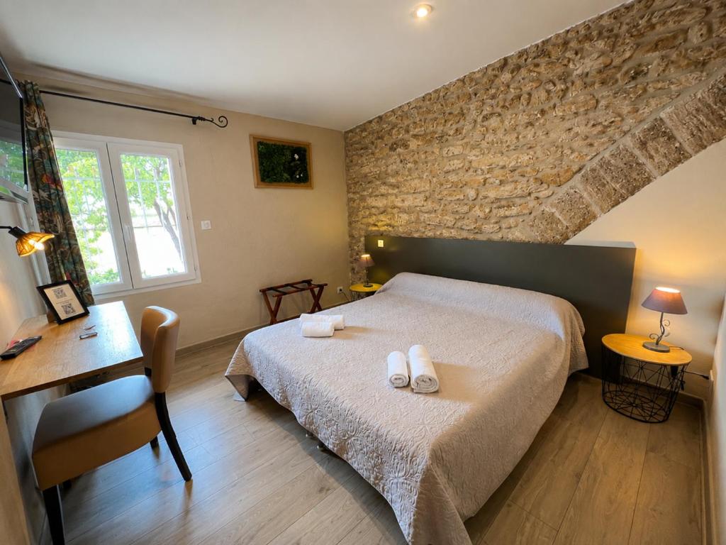 a bedroom with a bed with two towels on it at Hotel Saint Germain in Pézenas