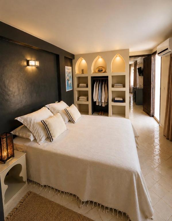 a bedroom with a large bed with white pillows at Studio Appartement Perdicaris en rez de jardin - maison dhotes Dar Tanja in Tangier