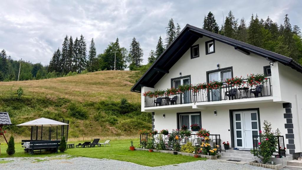 a white house with flowers on the balcony at Cabana de Sub Deal Arieșeni in Arieşeni