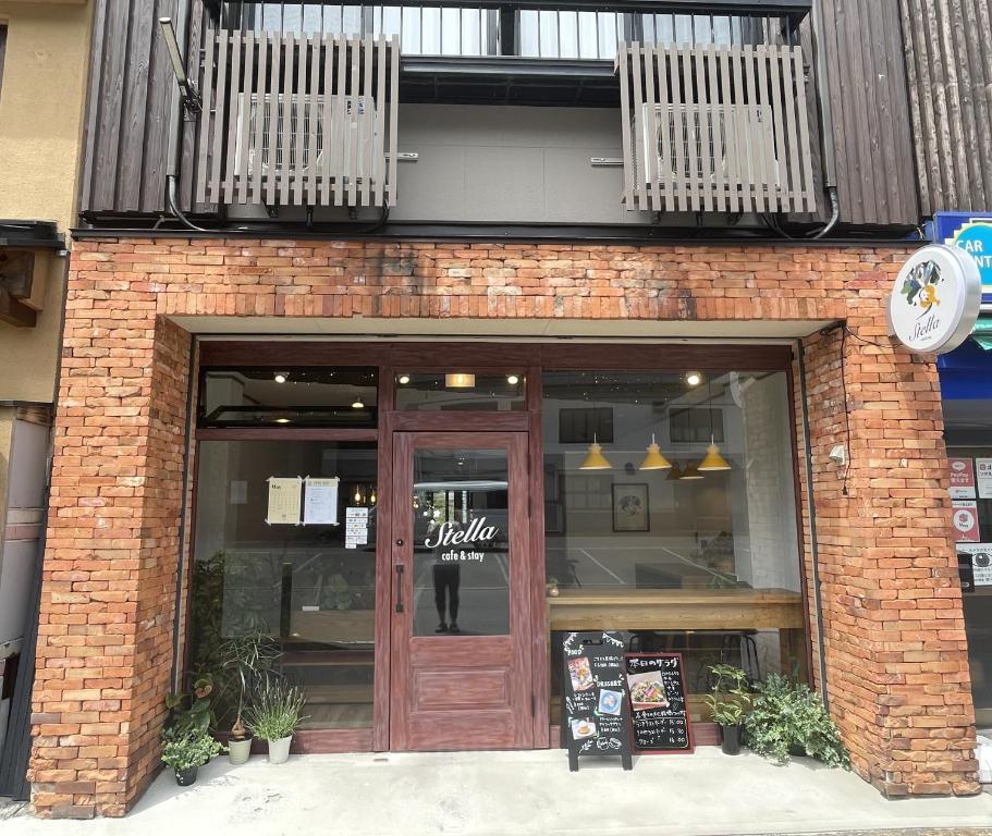 a brick store front with a wooden door and balcony at Cafe&Stay Stella in Minakami