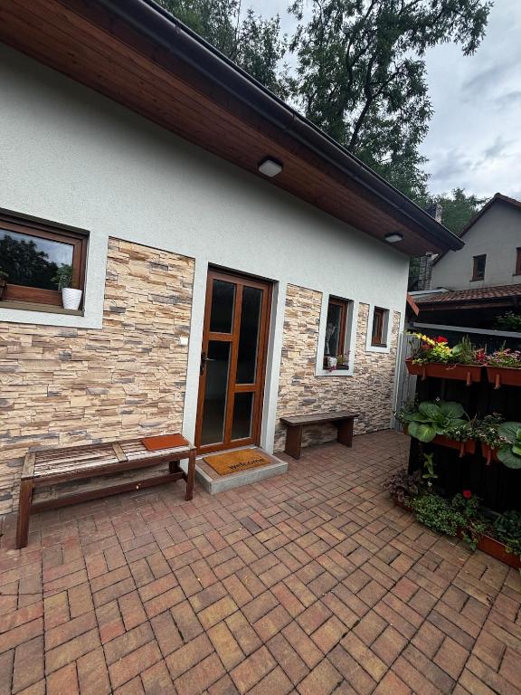a patio with a bench next to a building at Domek se zahrádkou in Zbečno