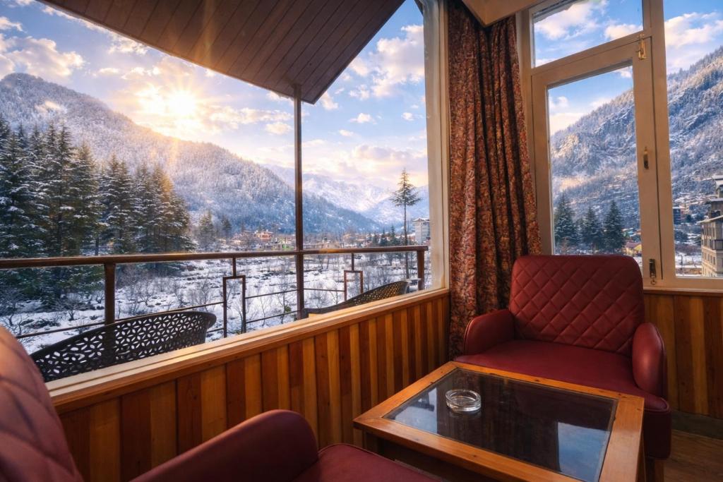 a room with a chair and a window with a view at Apple Flower Hotel - Personal Balcony, Lift, Garden and Mountain View in Manāli