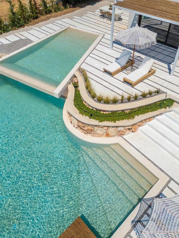a swimming pool with two lounge chairs and an umbrella at NeRó Villas Lefkada in Tsoukalades