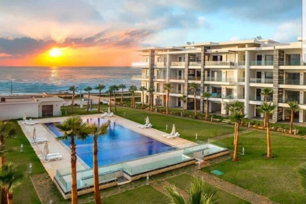 a large apartment building with a swimming pool and the ocean at Les belles terrasses mansouria in Mansouria