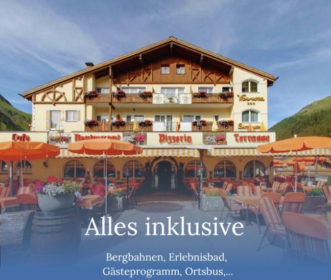 a large building with tables and chairs in front of it at Samnaunerhof Vital-Hotel in Samnaun