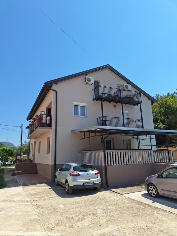 a house with two cars parked in front of it at Apartmani Medojević in Radanovići