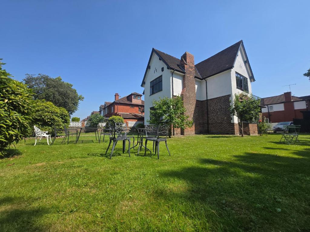 a group of tables in the grass in front of a building at Luxury Cottage Stay Rooms Free Wifi Old Trafford Manchester in Manchester