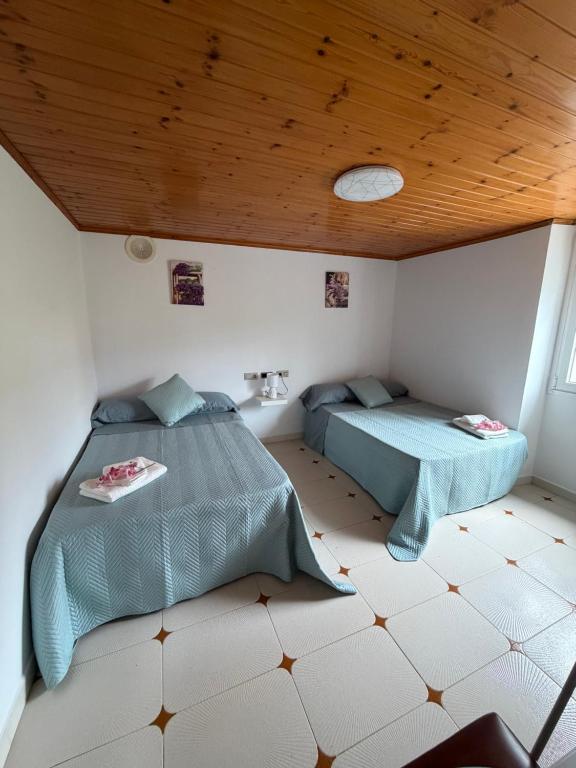 two beds in a room with a wooden ceiling at Casa Gallopin in Foz