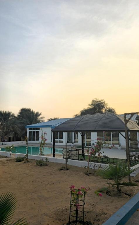 a pavilion with a table and benches and a building at Azure liwa in An Nashshāsh