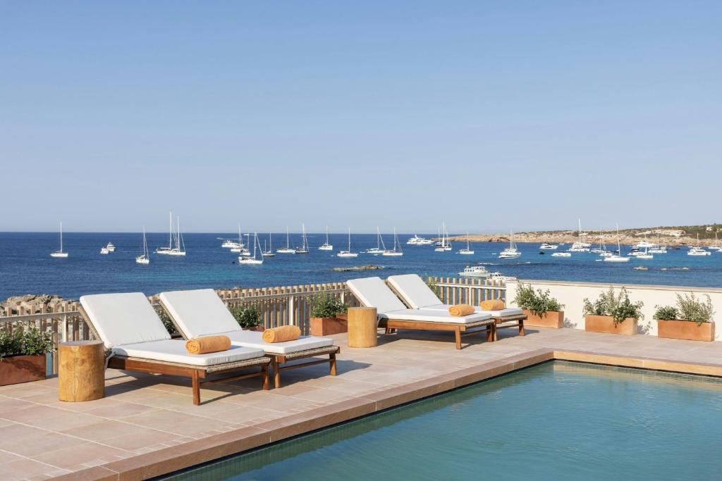 a row of lounge chairs sitting next to a swimming pool at Sabatic Formentera Autograph Collection in Es Pujols