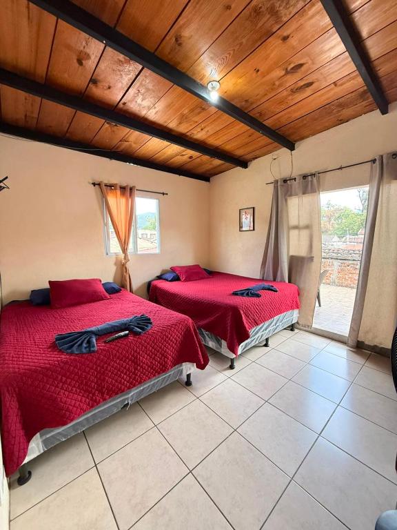 two beds in a room with a wooden ceiling at Cristales de Antigua Casa Cristal in Antigua Guatemala