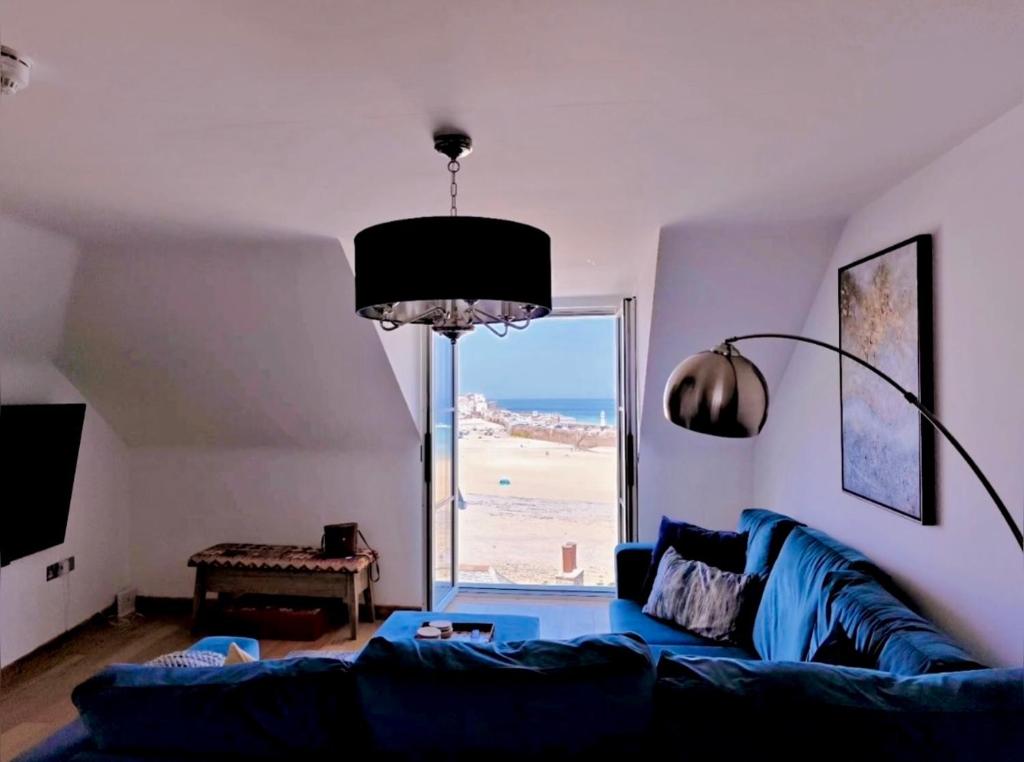 a living room with a blue couch and a large window at Blue Mist Apartment in St Ives