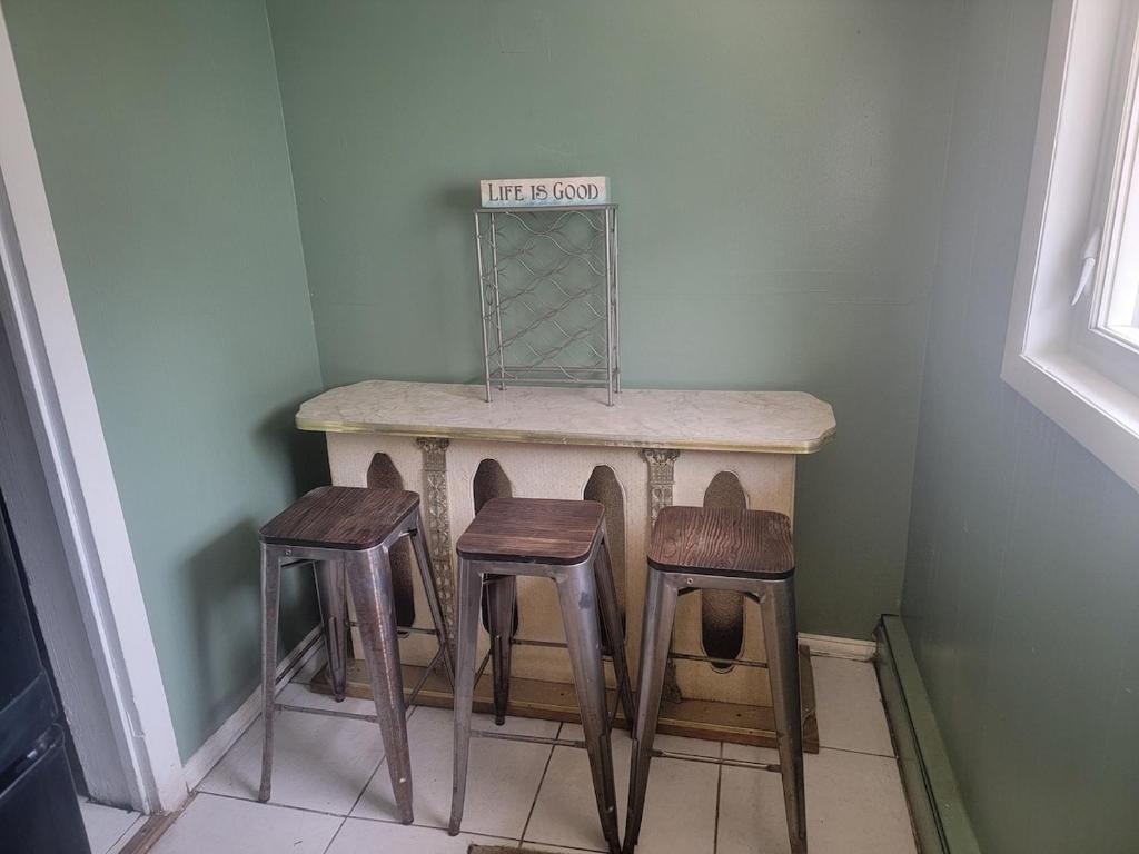a small table with three stools in a room at ARMANI MANOR rustic spacious 2br unit 1 in Wildwood