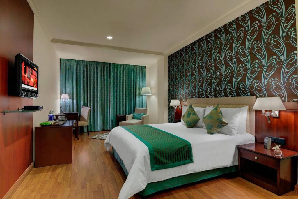 a hotel room with a large bed and a television at Royalton Hyderabad Abids in Hyderabad