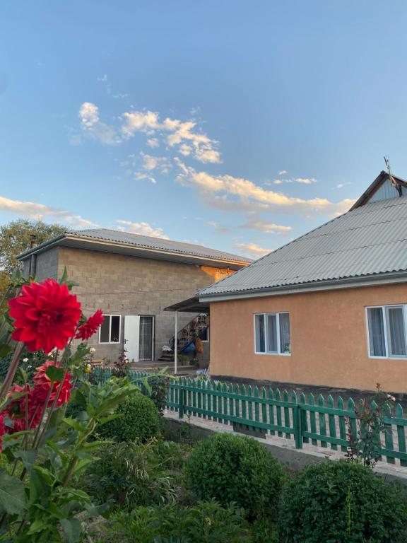 a house with a green fence and a red flower at Bloom Guest House in Tërt-Kul'
