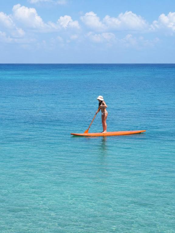 a woman is paddling on a surfboard in the ocean at Hotel Isla Azul - Islas del Rosario in Isla Grande