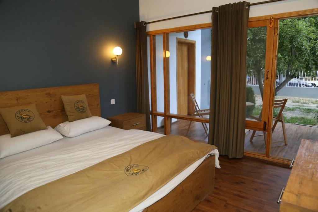 a bedroom with a large bed and a balcony at Hunza Oriole Hotel in Alīābād