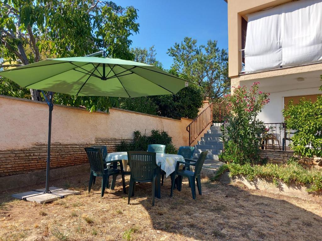 a table and chairs under a green umbrella at Apartman Branka in Ližnjan