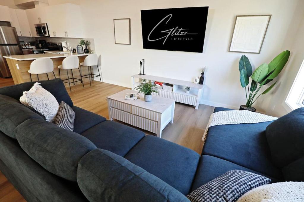 a living room with a blue couch and a kitchen at Central 5 Bedroom AC Rogers Commonwealth EXPO in Edmonton
