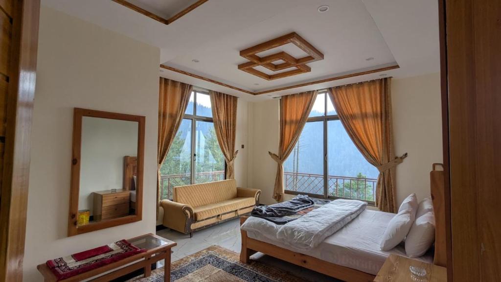 a bedroom with a bed and a mirror and a couch at Cool Pine Hotel Nathia Gali in Abbottabad