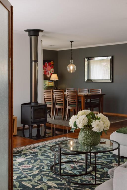 a living room with a stove and a table with flowers at Stylish 3BR Walk to Town in Trentham