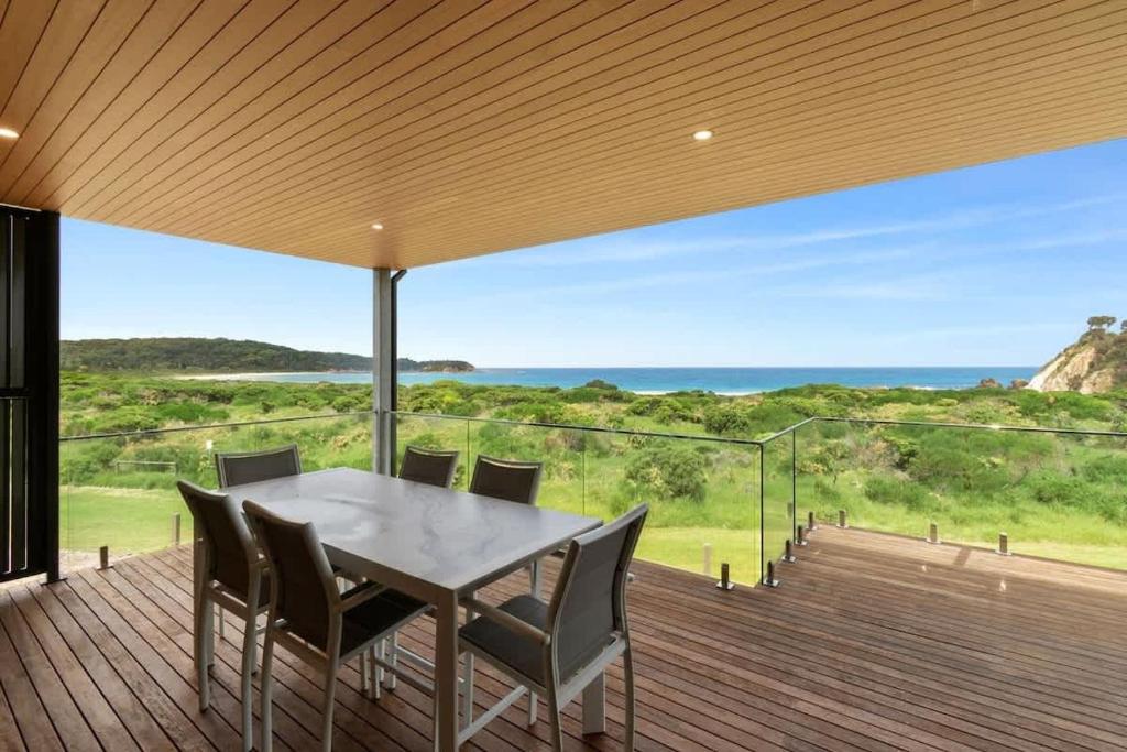a dining table on a deck with a view of the ocean at Dunes at Tomakin in Tomakin