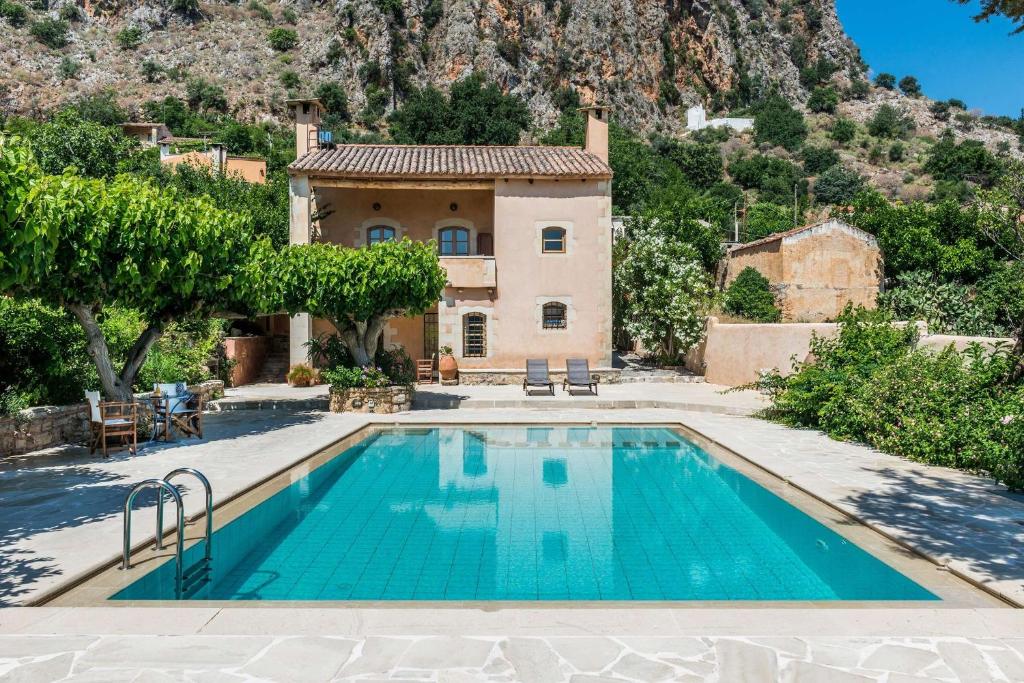 a house with a swimming pool in front of a mountain at Kamares Private Pool stone Villa in Makhairoí