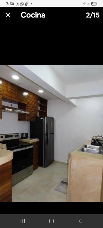 a kitchen with a black refrigerator and wooden cabinets at Casa puerto in Progreso