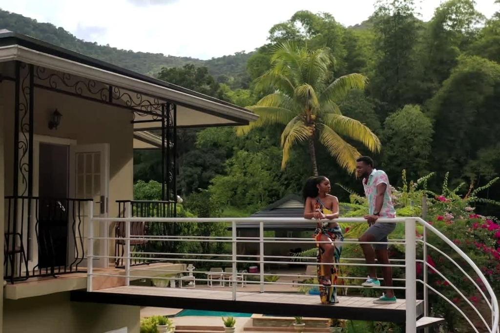 Ein Mann und eine Frau stehen auf dem Balkon eines Hauses. in der Unterkunft Bamboo View in Loango